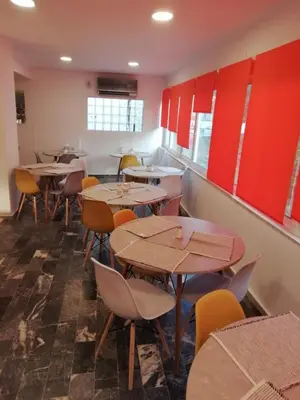a restaurant with tables and chairs and red cabinets at Helena Hotel in Rhodes Town