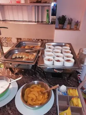 a counter with two trays of food and bowls of food at Helena Hotel in Rhodes Town