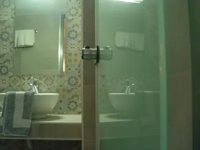 a bathroom with two sinks and a mirror and towels at Helena Hotel in Rhodes Town