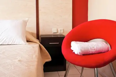 a red chair in a bedroom with a bed and a bed at Helena Hotel in Rhodes Town