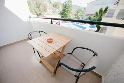a small wooden table and a chair on a balcony at Artemis Comfort&Pleasure in Faliraki