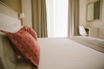 a bedroom with a bed with two red pillows on it at Artemis Comfort&Pleasure in Faliraki