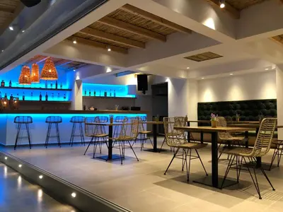 a restaurant with a bar with chairs and tables at Johannes Boutique Apartments & Suites in Afantou