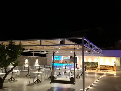 a patio with tables and chairs at night at Johannes Boutique Apartments & Suites in Afantou