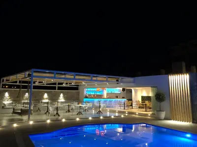 a swimming pool in front of a building at night at Johannes Boutique Apartments & Suites in Afantou