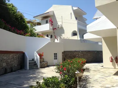 a white house with flowers in front of it at Johannes Boutique Apartments & Suites in Afantou
