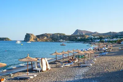 a beach with umbrellas and chairs and the water at Stegna Star Apartments in Archangelos