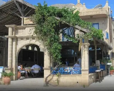 a building with an arch with people sitting at tables at Stegna Star Apartments in Archangelos
