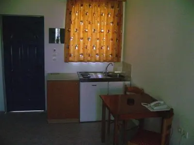 a kitchen with a stove and a table and a window at Stegna Star Apartments in Archangelos