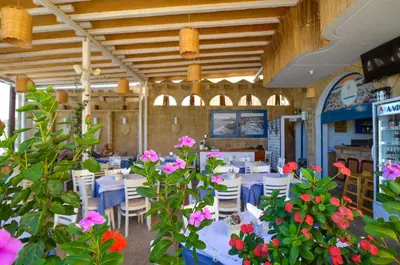a dining room with tables and chairs and flowers at Stegna Star Apartments in Archangelos
