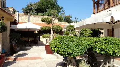 a patio with a hedge and an umbrella and a table at Paris Hotel in Rhodes Town