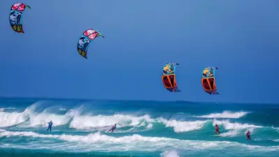 a group of people flying kites in the ocean at Matoula Beach in Ialyssos