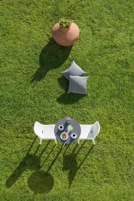 an overhead view of a table and bench on the grass at Matoula Beach in Ialyssos