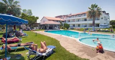 a group of people laying in lawn chairs near a swimming pool at Matoula Beach in Ialyssos