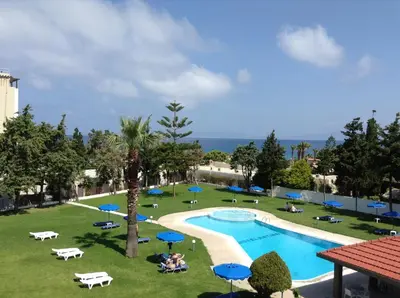 a view of a swimming pool with blue umbrellas at Matoula Beach in Ialyssos
