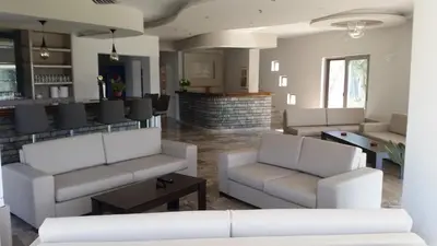 a living room with white couches and a bar at Saint George Resort in Archangelos
