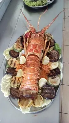 a lobster on a plate of food on a table at Saint George Resort in Archangelos