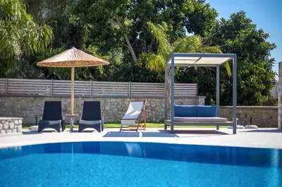 a group of chairs and an umbrella next to a pool at Madison Boutique, Faliraki in Faliraki