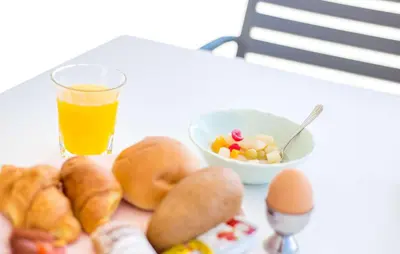 a table with a bowl of food and a glass of orange juice at Madison Boutique, Faliraki in Faliraki