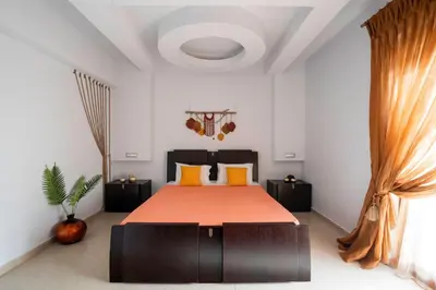a bedroom with a bed with orange sheets and a window at Maia Luxury Pool Villa in Afantou