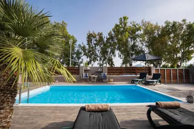 a swimming pool with two chairs and an umbrella at Maia Luxury Pool Villa in Afantou