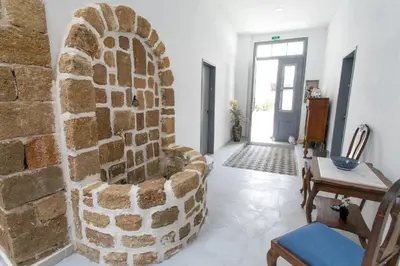 a living room with a stone wall and a chair at Mascot Boutique Hotel in Rhodes Town