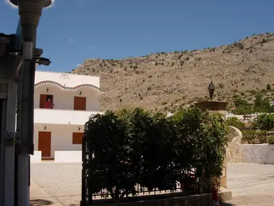a building with a fence in front of a mountain at Maria Apartments in Pefki Rhodes