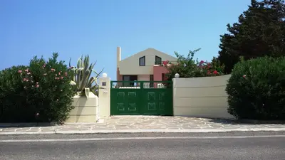 a white fence with a green gate in front of a house at Beachfront Villa SeaShell Superior in Gennadi