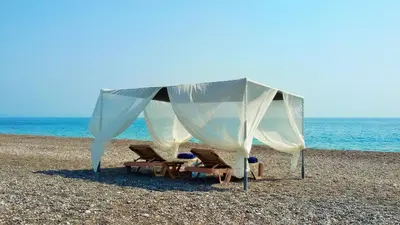 a tent on a beach with two chairs and the ocean at Beachfront Villa SeaShell Superior in Gennadi