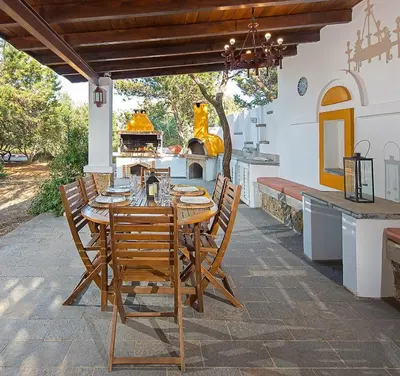 a wooden table and chairs on a patio with a fireplace at Beachfront Villa SeaShell Superior in Gennadi