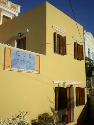 a yellow building with a sign on the side of it at Eos Studios in Symi