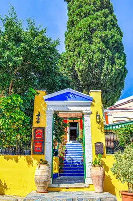 a yellow building with a blue door and trees at Symi Garden Studios in Symi