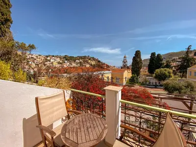 a balcony with a chair and a view of a city at Symi Garden Studios in Symi