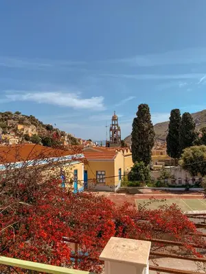 a view of a town with red flowers in front of a building at Symi Garden Studios in Symi
