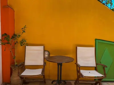 two chairs and a table in front of a wall at Symi Garden Studios in Symi