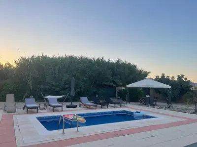 a swimming pool with lounge chairs and an umbrella at Summer Breeze Villa in Afantou