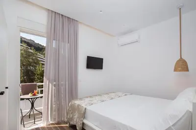 a white bedroom with a bed and a balcony at Elenis Philoxenia in Ixia