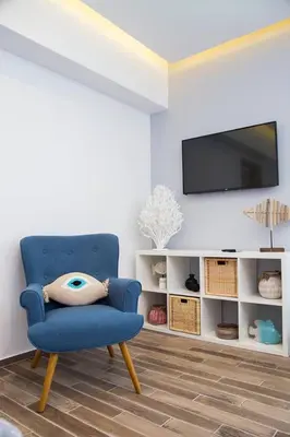 a living room with a blue chair and a tv at Elenis Philoxenia in Ixia