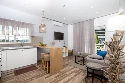 a kitchen and living room with white cabinets and a table at Elenis Philoxenia in Ixia