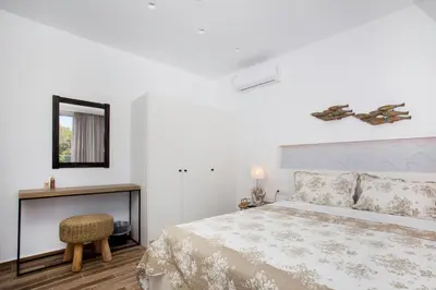 a bedroom with a bed and a table and a mirror at Elenis Philoxenia in Ixia