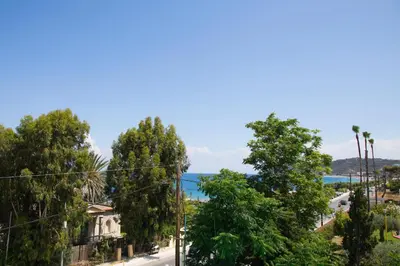 a city street with trees and the ocean in the background at Elenis Philoxenia in Ixia