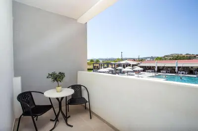 a balcony with a table and chairs and a pool at Tsampika Hotel Faliraki in Faliraki