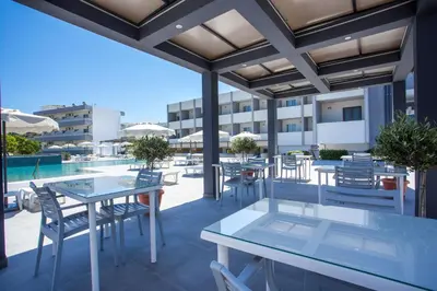 a patio with tables and chairs on a building at Tsampika Hotel Faliraki in Faliraki