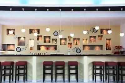 a bar with red bar stools and clocks on the wall at Rhodian Sun Hotel in Paradeísion
