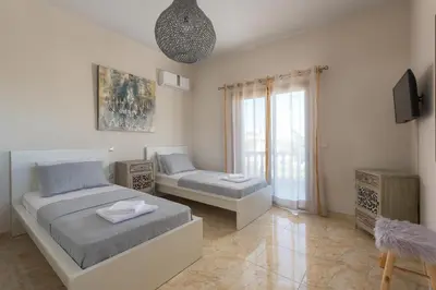 a bedroom with a bed and a couch and a tv at Evelyn Villa in Archangelos
