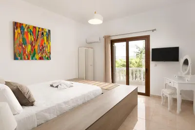 a bedroom with a bed and a desk and a painting at Evelyn Villa in Archangelos