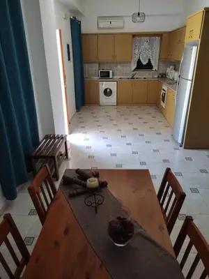 a kitchen with a wooden table and chairs and a kitchen with a refrigerator at Villa Cassandra in Halki