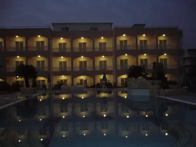 a large building with a swimming pool at night at Rhodian Rose Hotel in Faliraki