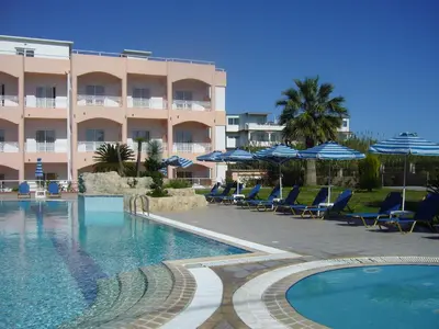 a hotel with chairs and umbrellas next to a swimming pool at Rhodian Rose Hotel in Faliraki