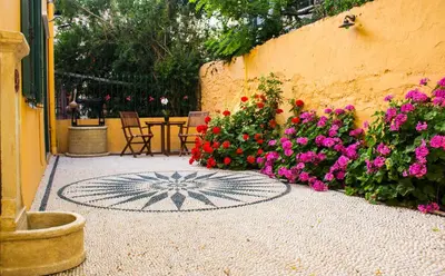 a patio with flowers and a table and chairs at Maison Masse - Historic Residence with Private Courtyard in Rhodes Town